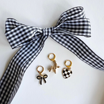Black and white checkered headband with three gold earrings on a white card featuring 'Leo + Lee' brand.