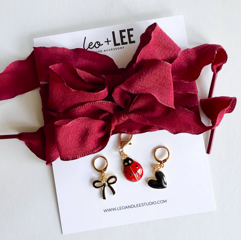 Three keychains on a card with 'leo + lee' branding, featuring a red bow, ladybug, and black cat design.