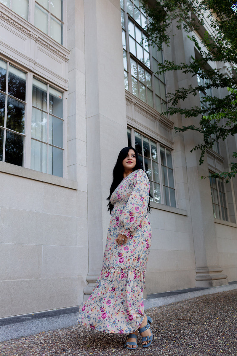 Romantic floral print maxi dress with smocking and tiered skirt, modeled on a sunny day in front of stone architecture