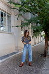 Woman wearing light wash barrel-leg jeans with tie belt