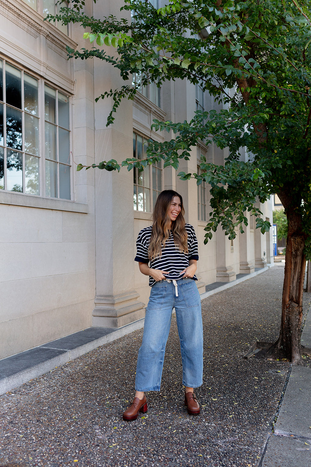 Woman wearing light wash barrel-leg jeans with tie belt