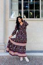 Woman in a floral dress standing outdoors with a building and window in the background