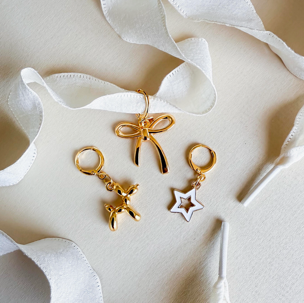 A shiny gold bow charm 🎀 hanging from a sneaker lace for a chic and girly touch.