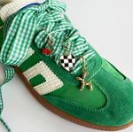 Green shoe with decorative ribbons and charms on a white background