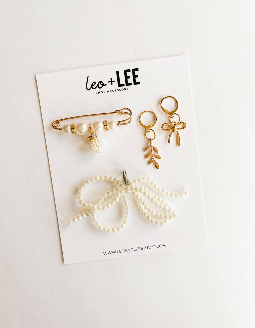Set of shoe accessories including pins and clips on a white card with 'Leo + Lee' branding.